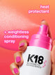 K18 heat protectant and conditioning spray with a hand holding the bottle against a pink background